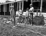 Finishing the stonework skirt around the foundation.  Left, in overalls, Thomas Brusveen, the others haven't been identified.